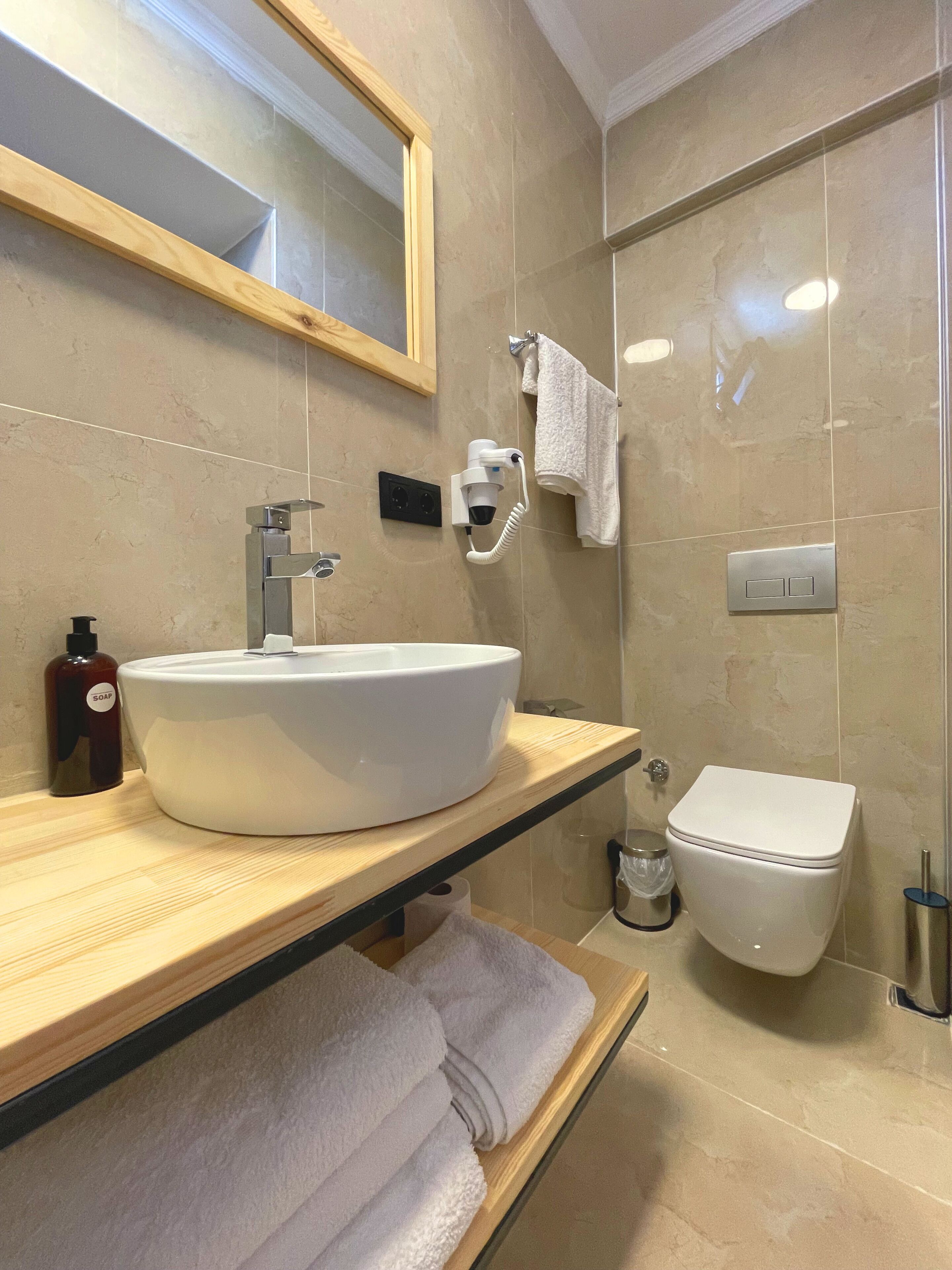 A bathroom with a large white sink, a mirror, a towel rack, a toilet, and a shower area.