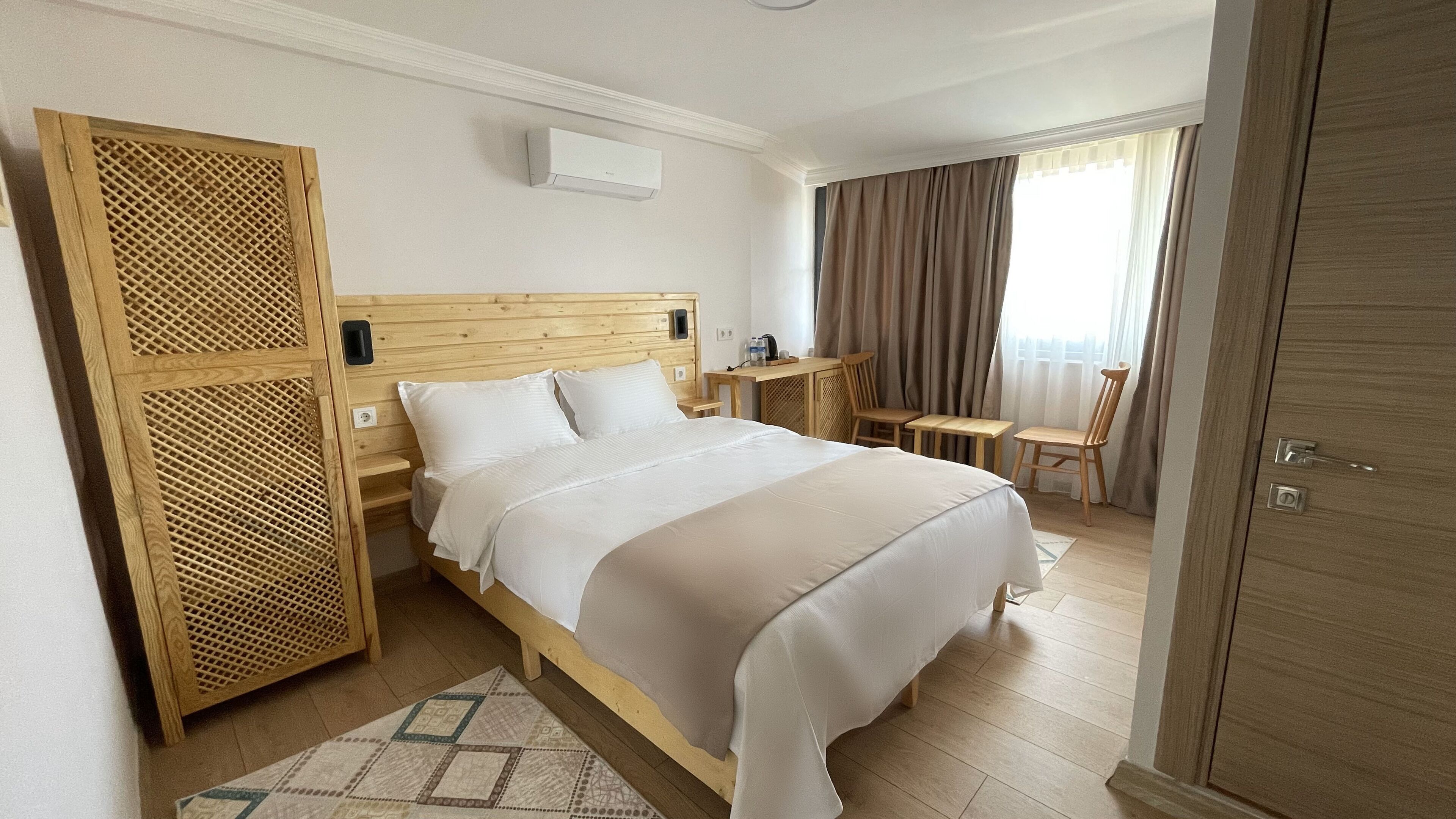 Een hotelkamer met een houten bed, een bureau, een stoel en een kledingkast.