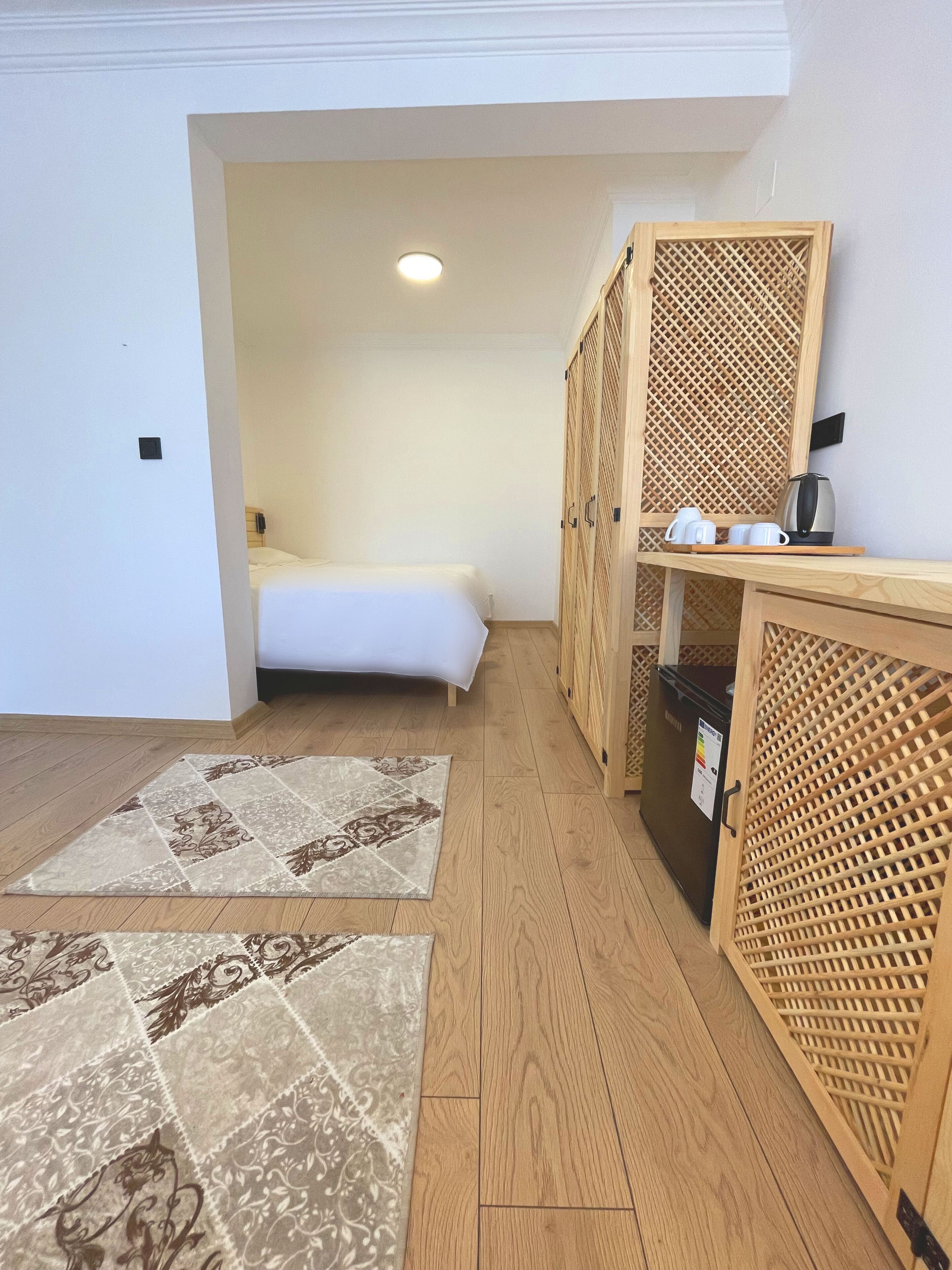 Ein Schlafzimmer mit einem Bett, einem Holzschrank und einer kleinen Küchenzeile.
