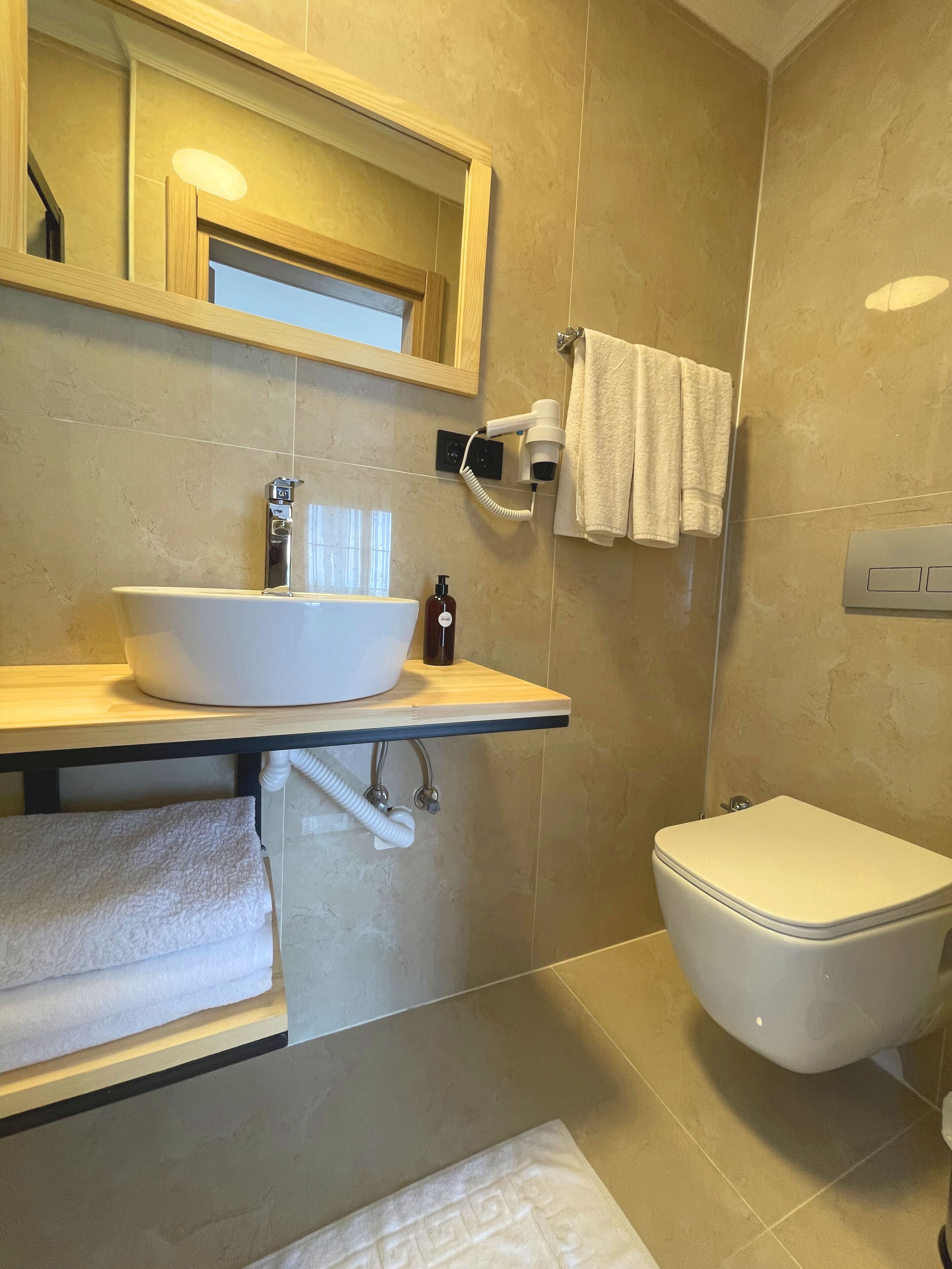 Un baño con lavamanos blanco, inodoro y espejo.