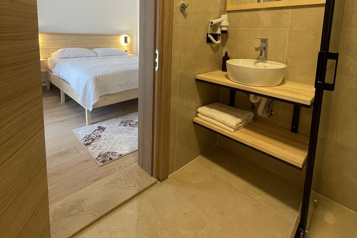 A modern bathroom with a sink, mirror, and towel rack.