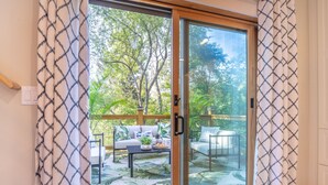 Eine Glastür zur Terrasse mit einer Couch, einem Tisch und Topfpflanzen.