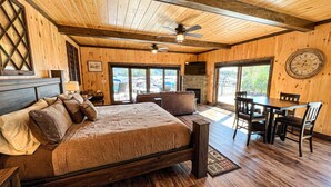 A wooden cabin room with a bed, a dining table, and chairs. - Waterfront Lookout (Bolton)