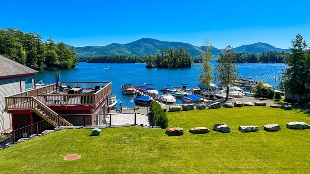 A lakeside property with a dock, boats, and a building with a deck. - Waterfront Lookout (Bolton)