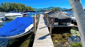 A wooden dock leading to boats, a sign warning of no lifeguard, and a clear view of the lake and mountains. - Waterfront Lookout (Bolton)