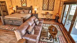 A cozy wooden room with a bed, a leather sofa, and a small table. - Waterfront Lookout (Bolton)