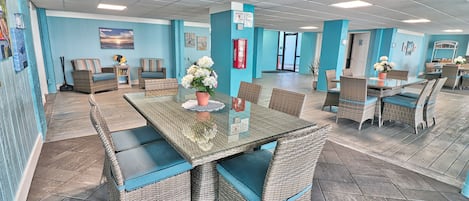 Amplio espacio interior con mobiliario de mimbre, una mesa de vidrio y una pared azul.