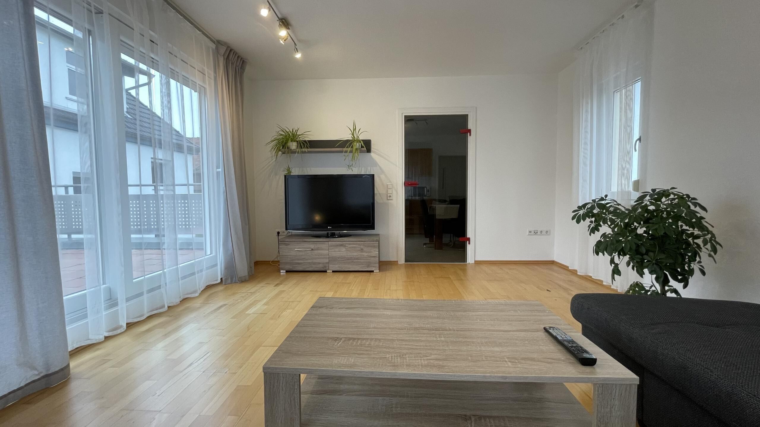 A modern living room with a flat-screen TV, wooden coffee table, and a sofa.