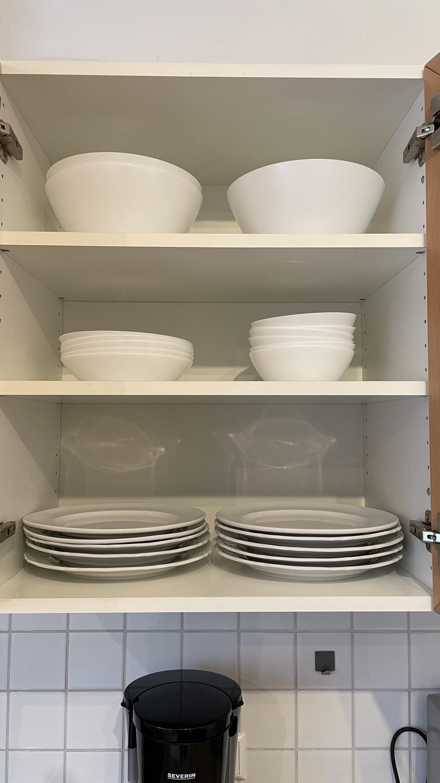 A kitchen with white shelves holding bowls and plates.