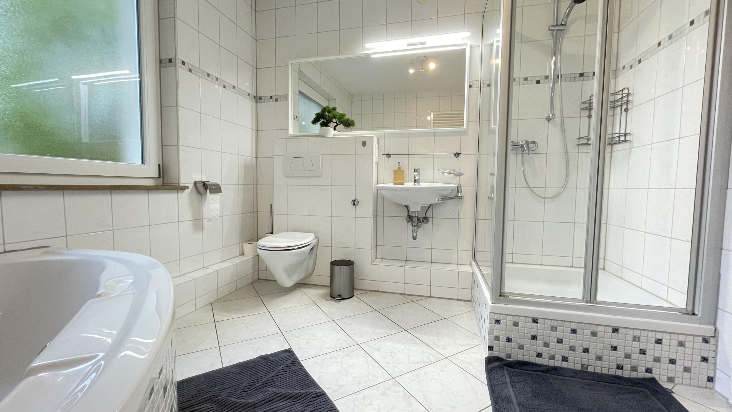 A modern bathroom with a bathtub, toilet, sink, and glass-enclosed shower.