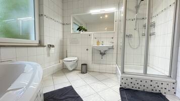Un baño moderno con bañera, inodoro, lavamanos y ducha envuelta en vidrio.