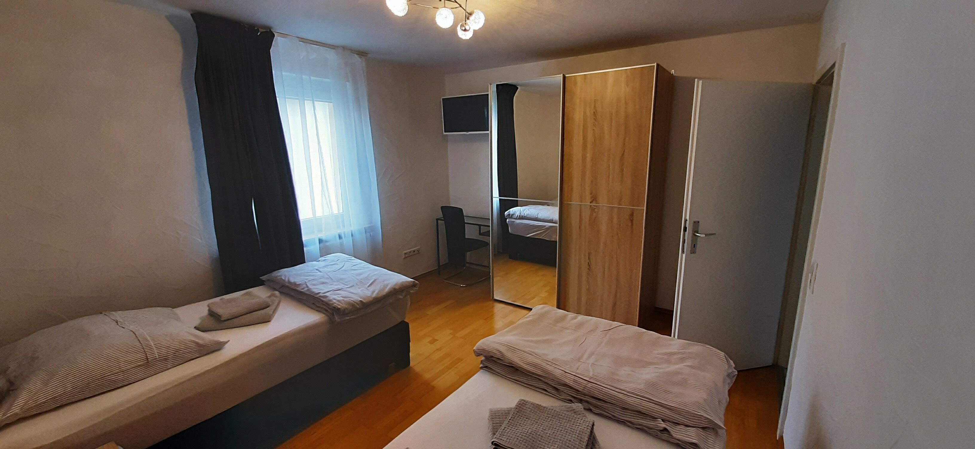Une chambre à coucher de taille réduite, comprenant un lit, une table de chevet, un miroir et une armoire.
