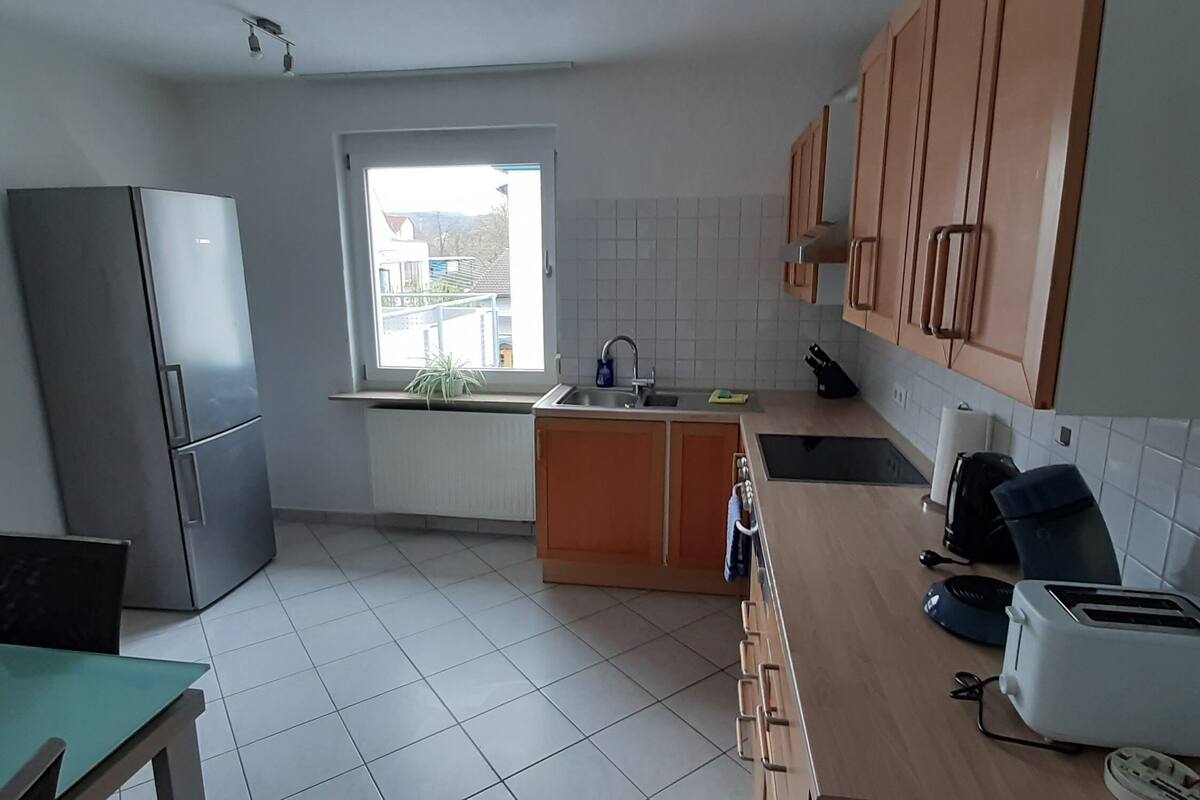 A compact kitchen with a refrigerator, sink, and a window providing natural light.