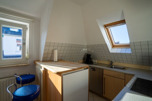 Cocina compacta con ventana, lavamanos y lavavajillas.