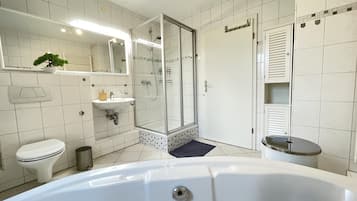 Une salle de bain moderne avec une douche à parois de verre, un lavabo blanc et une baignoire.
