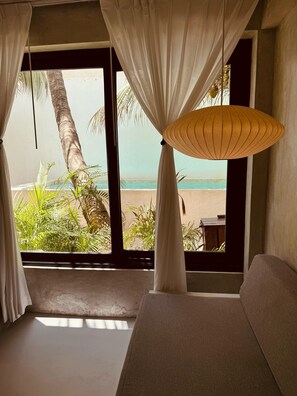 A room with a large window, white curtains, a hanging lamp, and a view of the beach. - Apartments & Suites MADRE Holbox Self-Check IN (Isla Holbox)