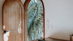 A room with a wooden door, a white cabinet with drawers, and a small table with a black object on it. - Apartments & Suites MADRE Holbox Self-Check IN (Isla Holbox)
