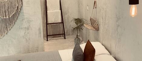 Un dormitorio moderno con cama, almohadas, una planta colgante, una escalera y una hamaca.