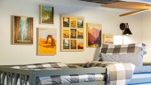 Une chambre avec un lit, une lampe fixée au mur et des affiches représentant des parcs nationaux.
