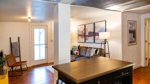 Un salon moderne avec une table à manger en bois, un canapé agrémenté de coussins colorés, un lampadaire et un tableau encadré accroché au mur.