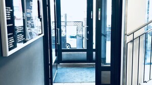 A hotel entrance with a dark carpeted hallway leading to a glass door. - Kotimaailma Pori Center (Pori)