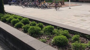 A paved outdoor area with a row of bicycles parked along the edge. - Kotimaailma Pori Center (Pori)