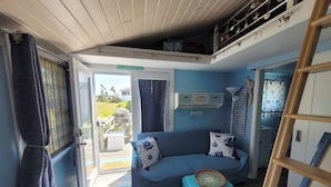 Un espacio habitable pequeño con un sofá, un taburete y una escalera.