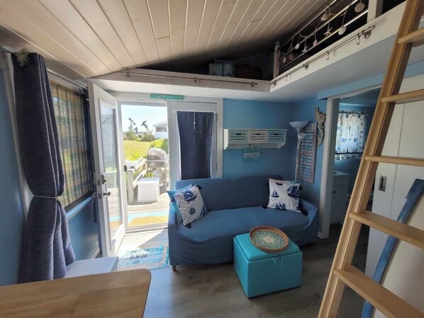 A compact living space with a sofa, a small ottoman, and a ladder.