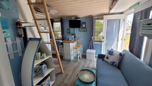 Un espacio habitable compacto con kitchenette, un sofá, una escalera y una pequeña mesa.