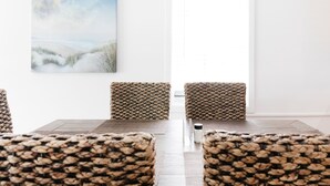 Un coin repas avec une table et des chaises, un tableau accroché au mur et une fenêtre avec des stores.