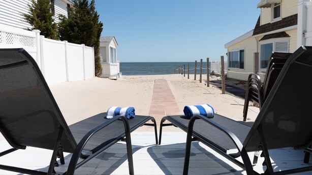 Une plage avec deux chaises longues et un sentier menant à l’eau.