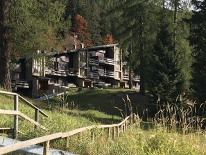 A modern building with multiple balconies, surrounded by dense forest. - HOFER APARTMENT MhD (Madonna di Campiglio)