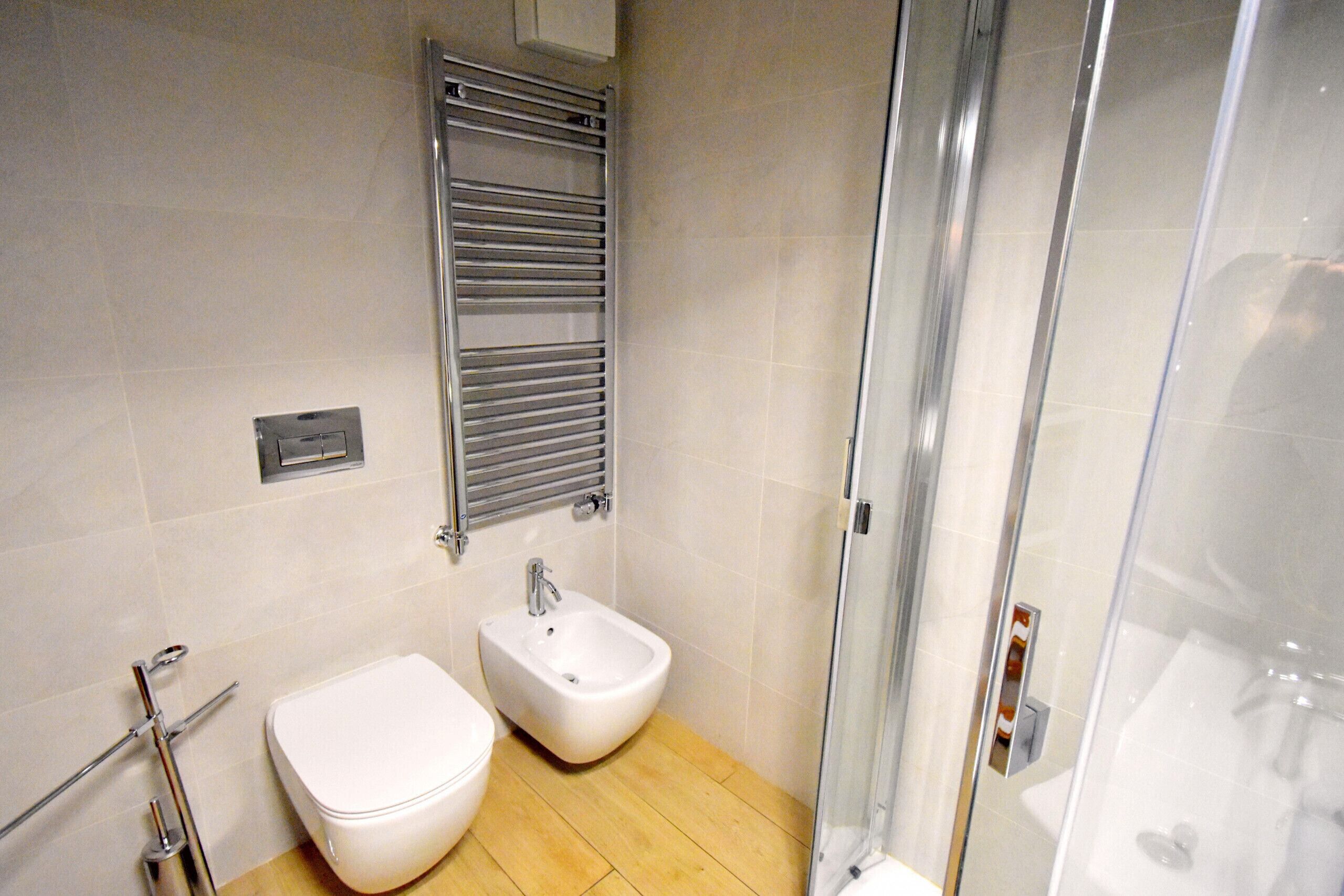 Ein Badezimmer mit Toilette, Bidet und einer Duschkabine aus Glas.