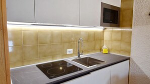 Uma cozinha moderna com armários brancos, uma pia dupla e um micro-ondas.