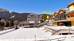 Estância de esqui coberta de neve com um edifício de vários andares com a placa 'Palacampiglio'.