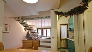 Ein Essbereich mit einem Holztisch, einem Weihnachtsbaum und einer Treppe, die zur Küche führt.