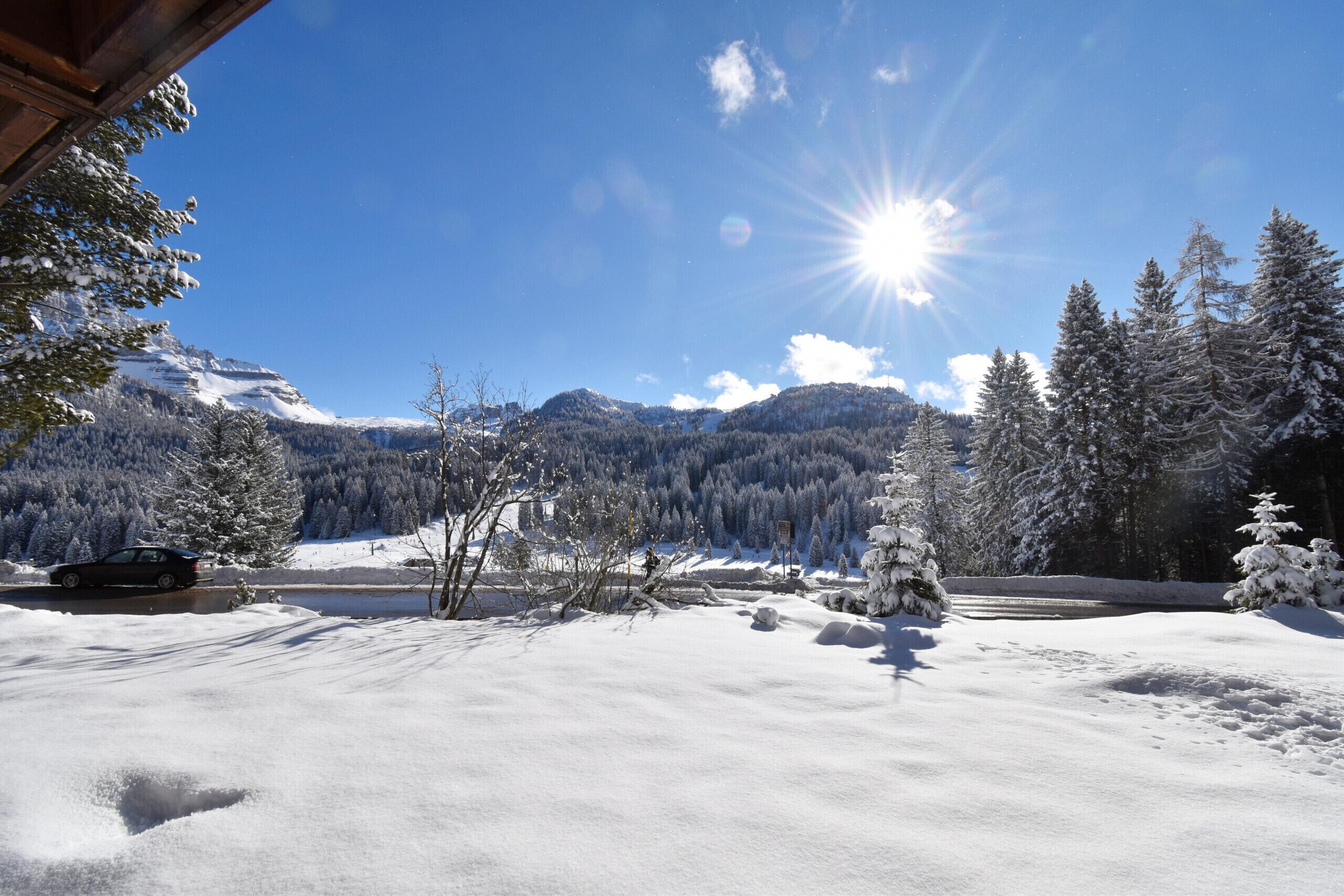 Un paysage enneigé avec des montagnes, un ciel dégagé et un chalet.