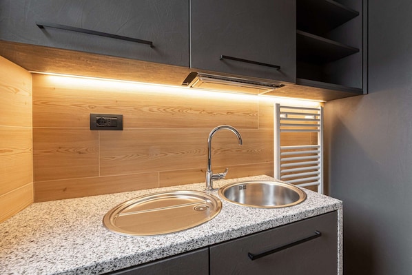 Eine Küche mit zwei Edelstahl-Spülen, einer Holzrückwand und einem modernen Wasserhahn.