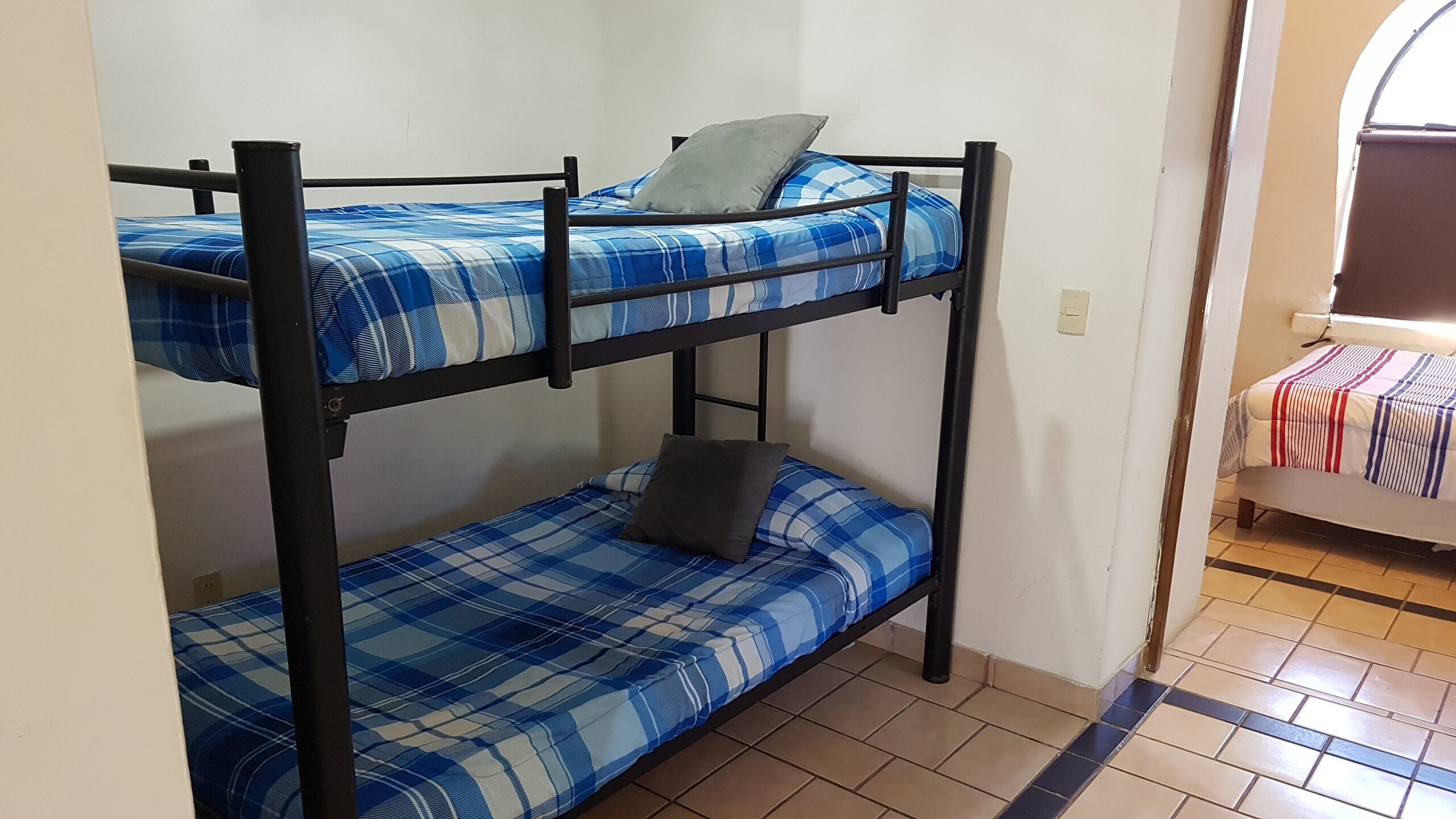 Un lit superposé avec une couette à carreaux bleus et blancs, un oreiller gris sur le lit du haut et un oreiller marron sur le lit du bas.