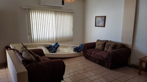 A living room with a sofa, a small table, and a window with blinds. - Departamento Zona Dorada Mazatlán 6 (Mazatlán)