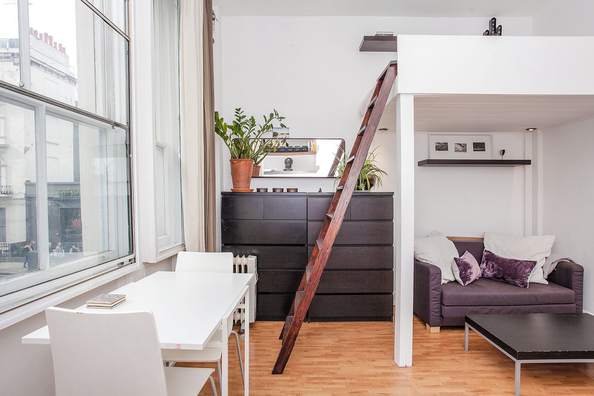Un espacio moderno para vivir con una mesa blanca, un sofá y una escalera.