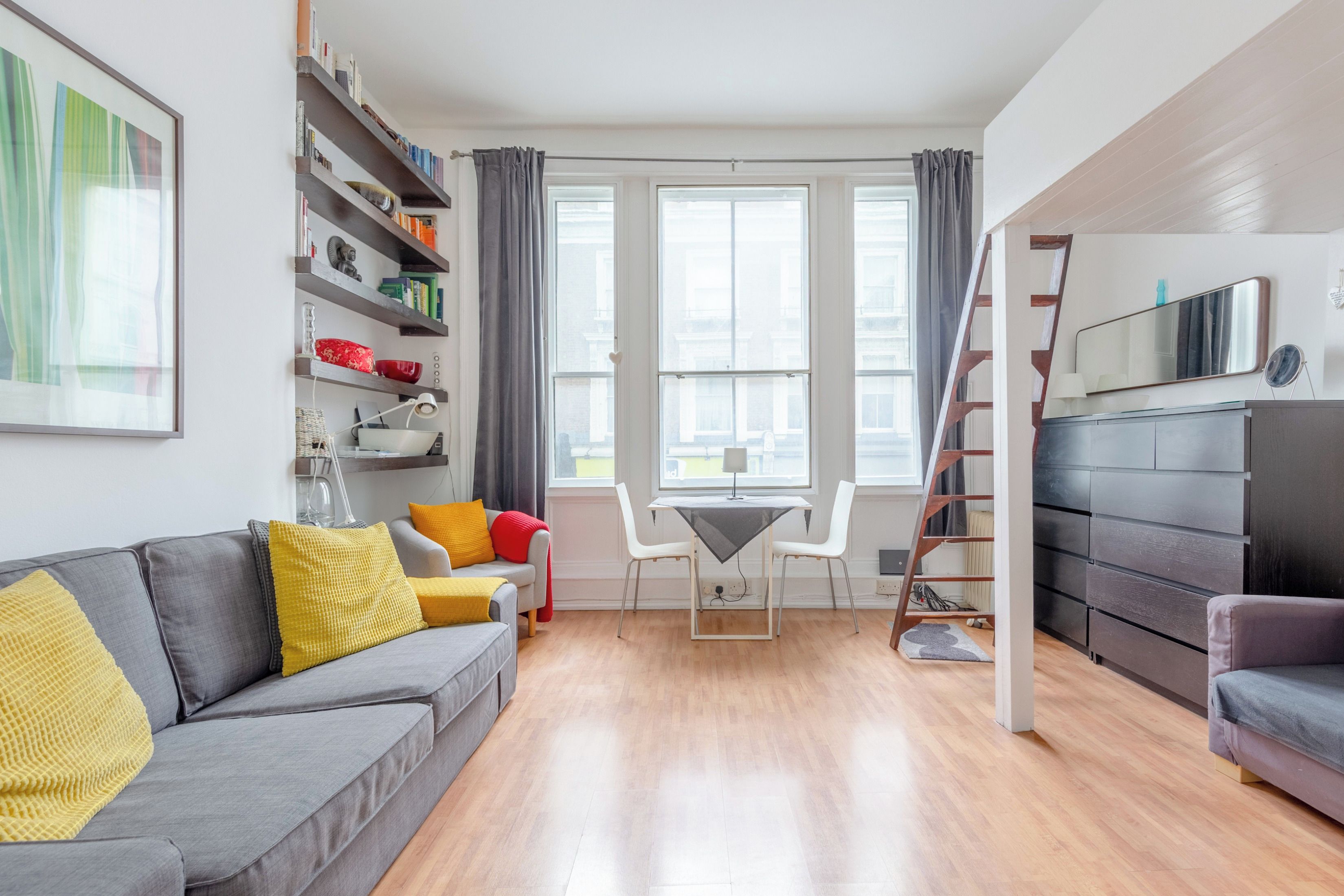 A modern living room with a grey sofa, a small table, and a bookshelf.