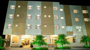 Un hotel de varios pisos con fachada moderna, que cuenta con una entrada central con dosel y varios balcones.