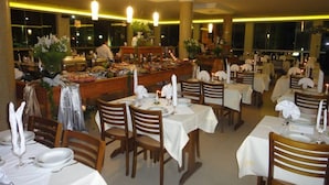 Un restaurante con varias mesas dispuestas para comer, una zona de bufé al fondo y un ambiente cálido y acogedor.