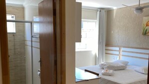 Una habitación de hotel con cama, ducha y vistas al exterior.