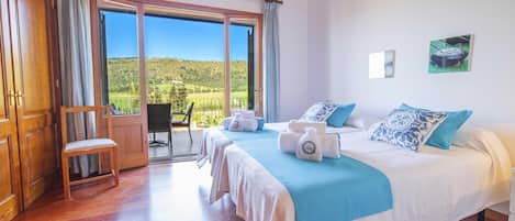 A hotel room with a large bed, a chair, a table, and a view of the countryside.