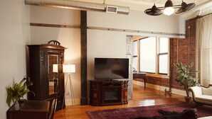Una sala de estar con televisor, mueble de madera y un ventanal grande.