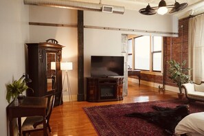 A living room with a TV, wooden cabinet, and a large window. - Incredible Spacious & Luxurious 6 Bed Loft w/ Gym (Monmouth)