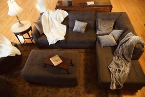 A cozy living room with a sectional sofa, a small side table, and a coffee table. - Incredible Spacious & Luxurious 6 Bed Loft w/ Gym (Monmouth)