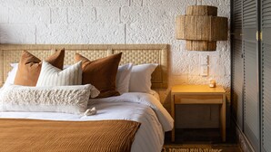 Ein Schlafzimmer mit einem großen Bett, einem Nachttisch, einer Lampe und einer strukturierten Wand.